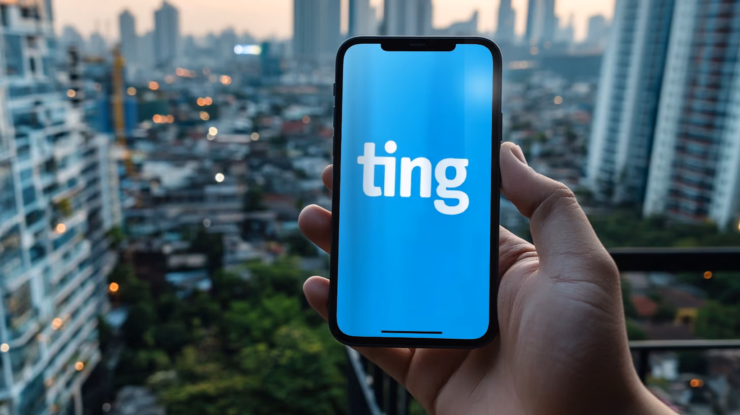 A person holding a smartphone outdoors, with ting mobile logo on the screen