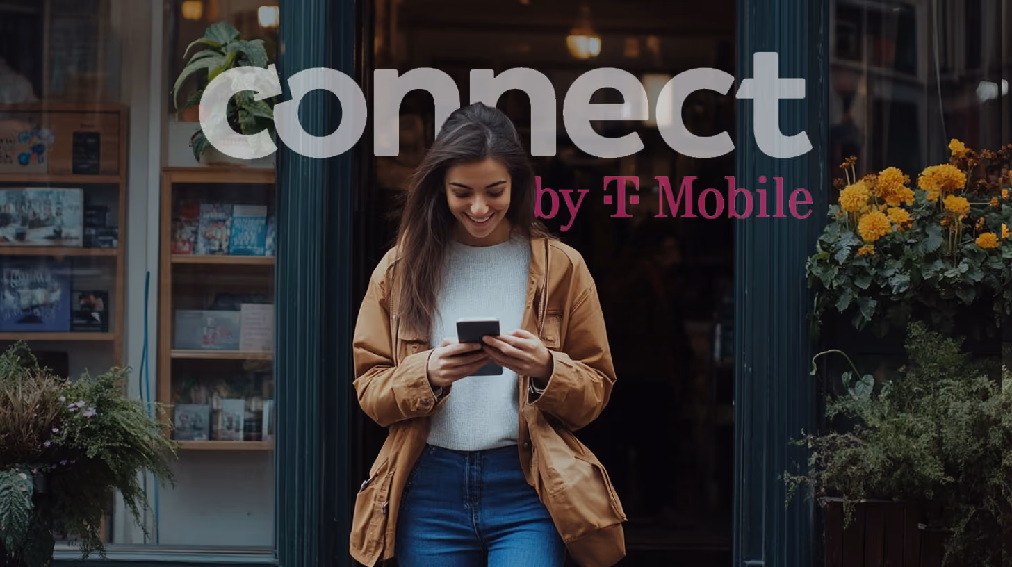 A happy woman is walking in front of a shop at afternoon, holding and watching her phone