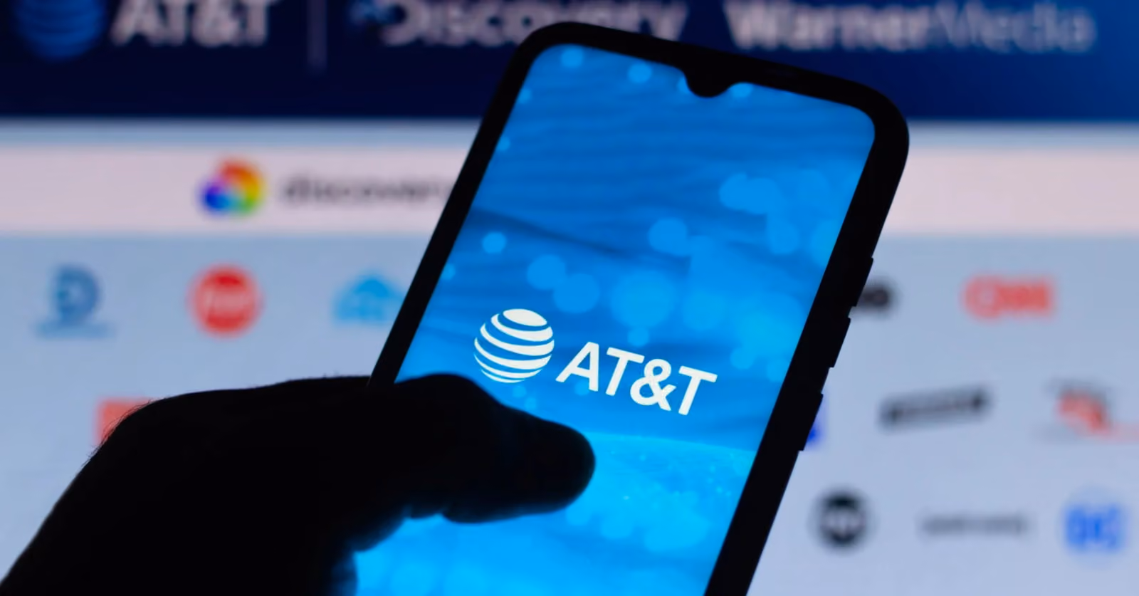 Hand holding a smartphone with AT&T logo on the screen