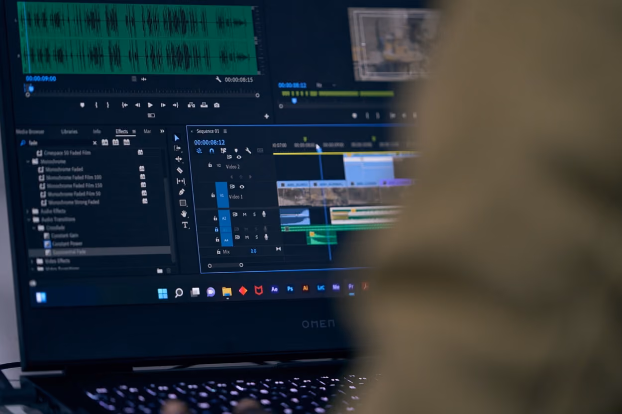 A person focused on their laptop, engaged in work, with a professional setting in the background.