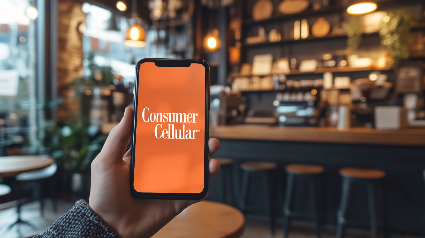 A person holding a smartphone with Consumer Cellular logo on the screen