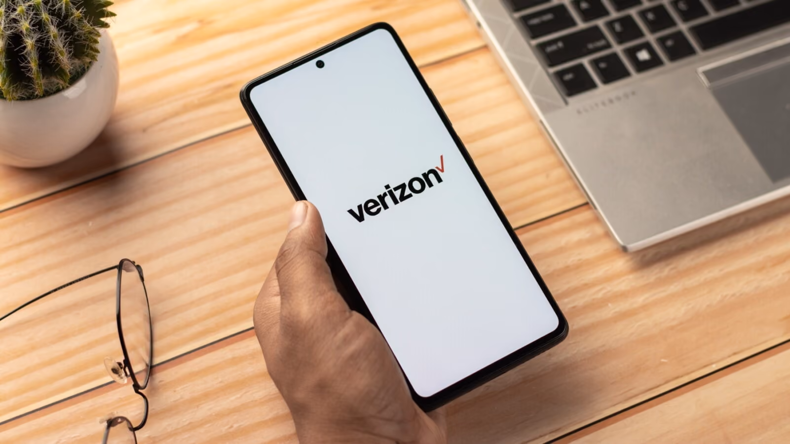 Hand holding a smartphone with Verizon logo on the screen