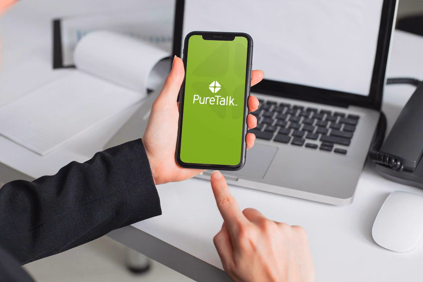 A person holding a smartphone with puretalk logo on the screen