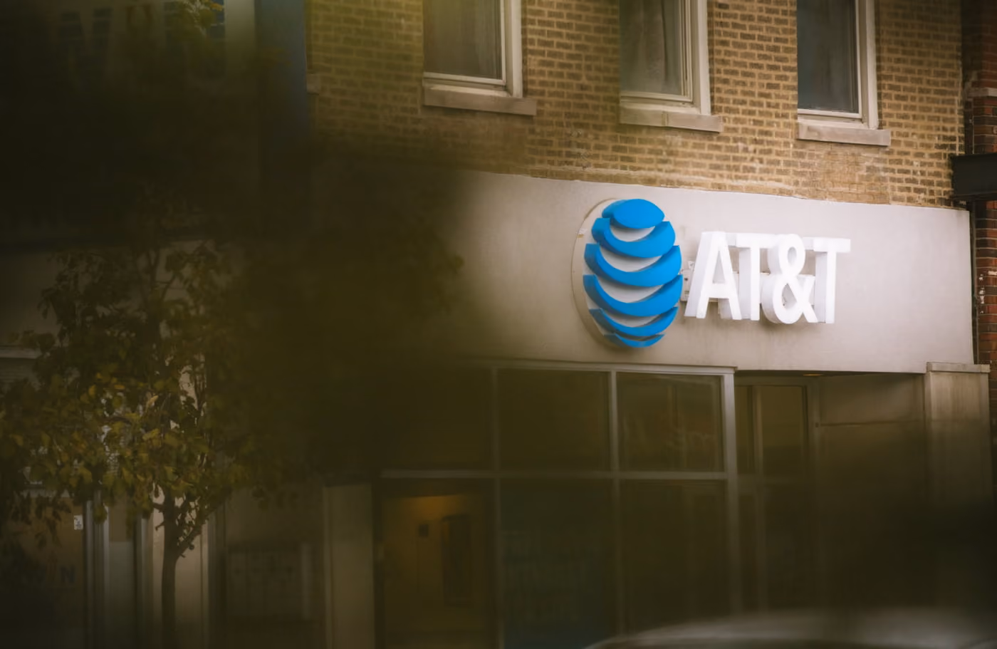 A vehicle parked in front of an AT&T store, with the store's logo visible and the car positioned on the sidewalk.