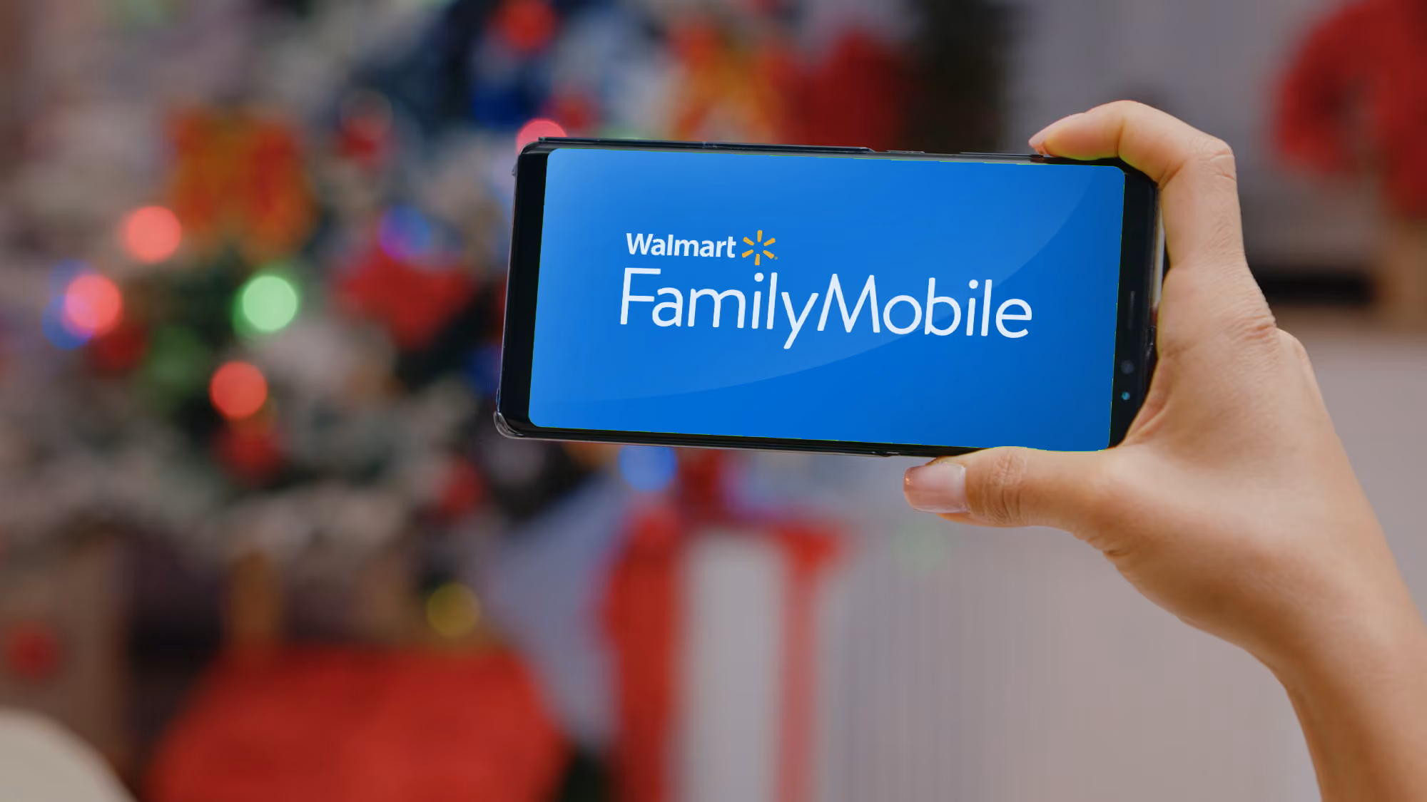 A person holding a smartphone with family mobile logo onthe screen