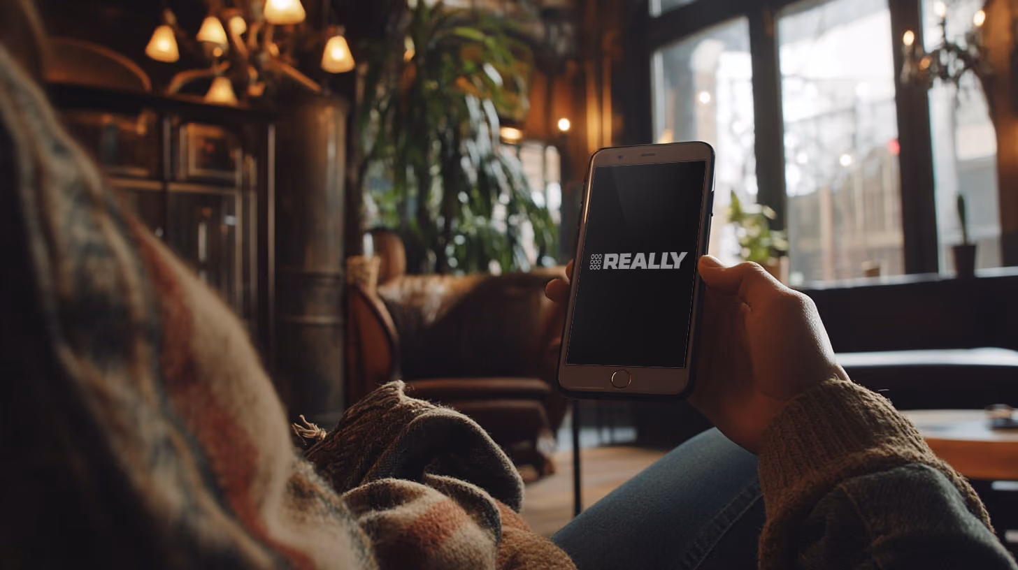 A person holding a smartphone, with REALLY Wireless logo on the screen