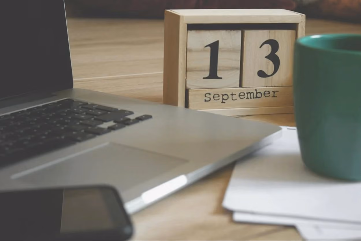 A laptop and calenderon the top of desk