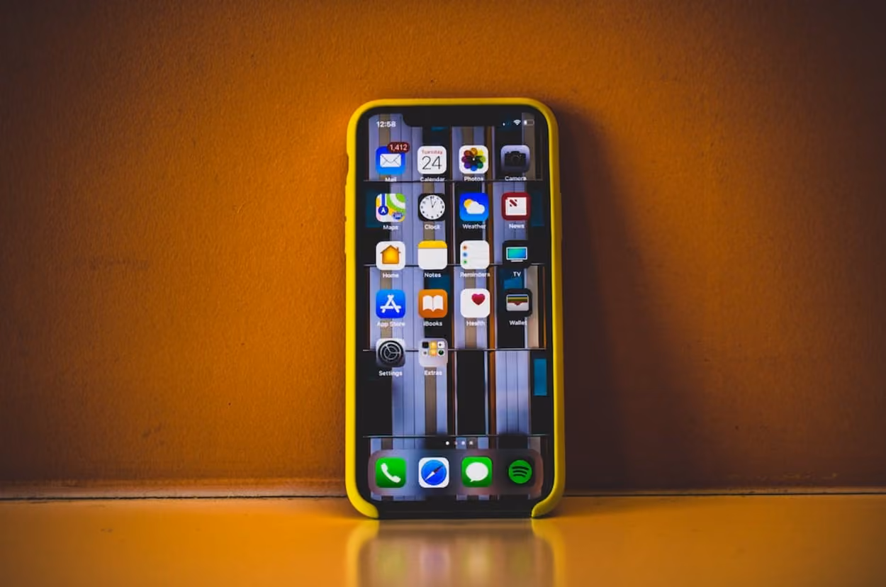 An iPhone rests on a table, set against a vibrant yellow background, showcasing its sleek design and modern aesthetics.