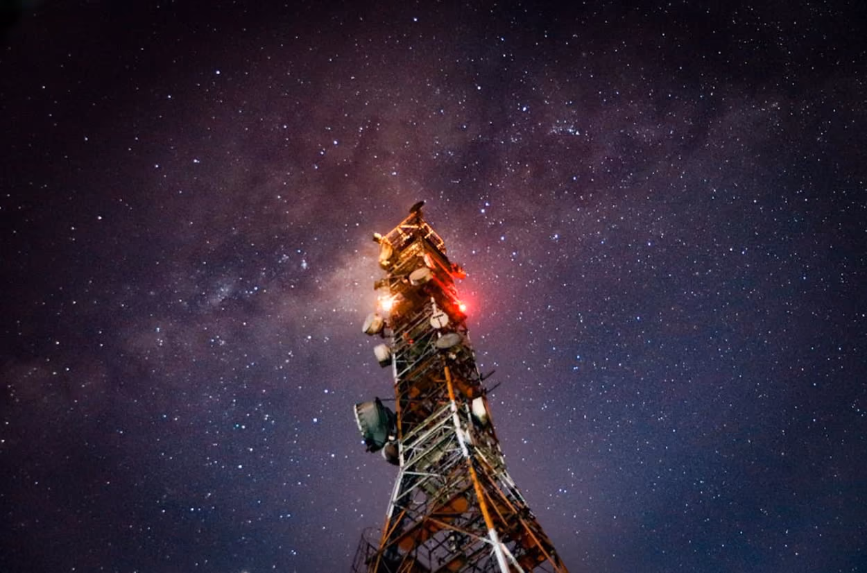 A cell tower silhouetted against a starry night sky, showcasing the beauty of technology and nature intertwined.