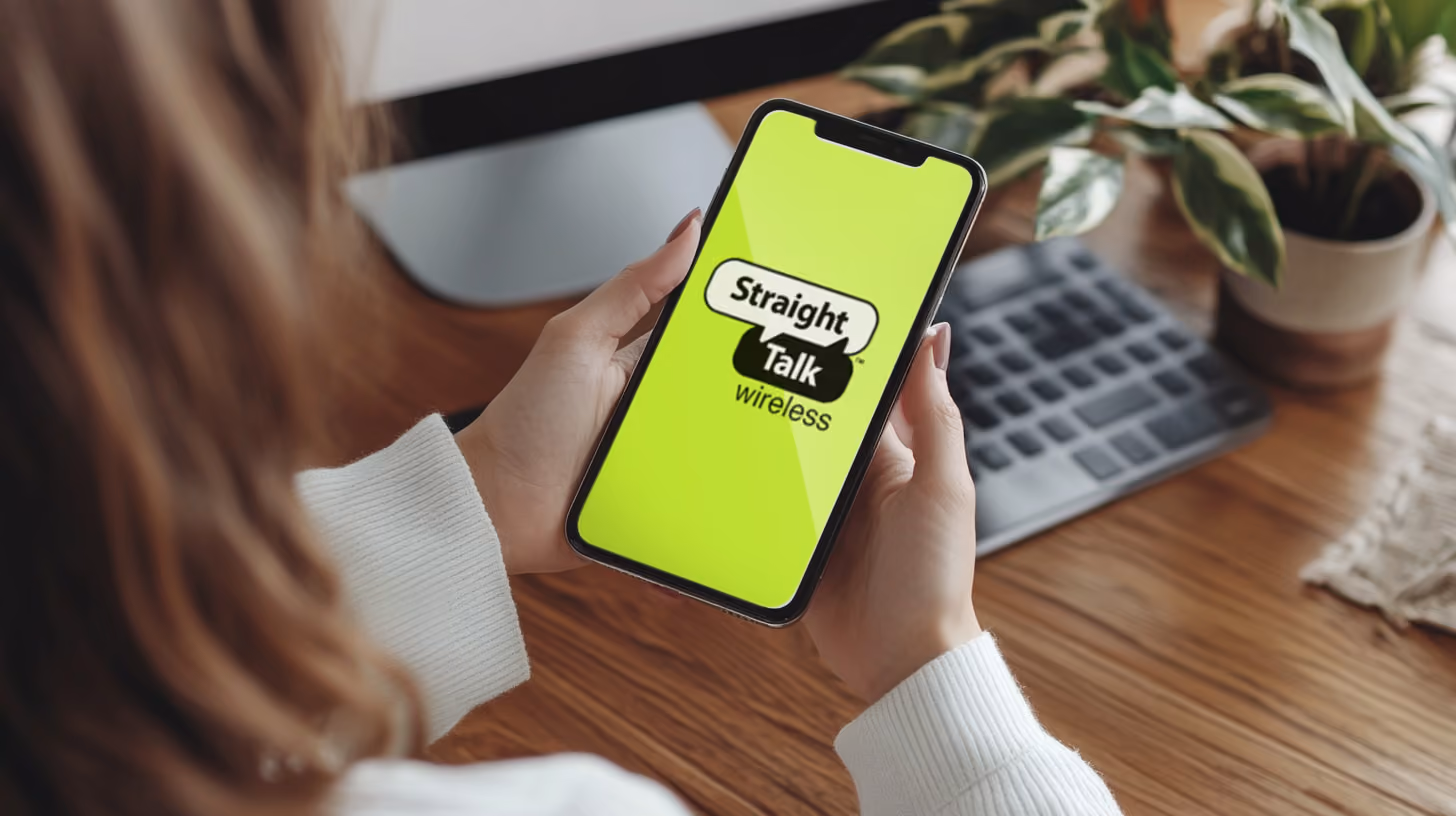 A person holding a smartphone with straight talk logo on the screen