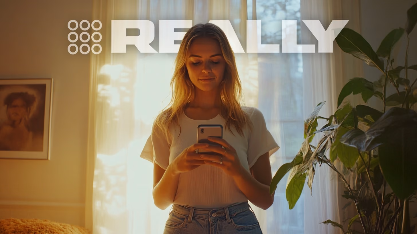 smiling woman watching on her phone, standing in her family room, happy vibes 