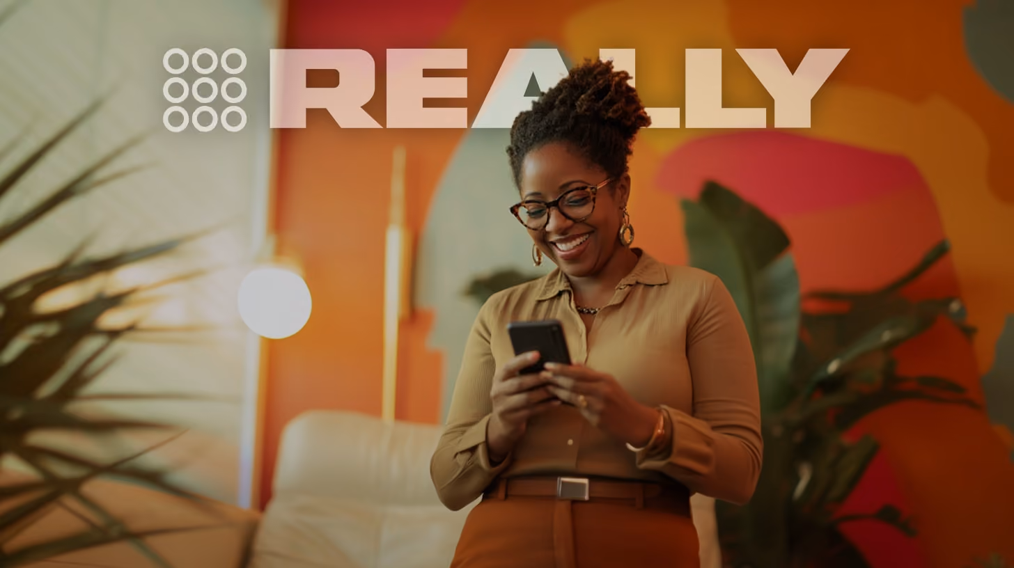 smiling woman watching on her phone, standing in her office, happy vibes