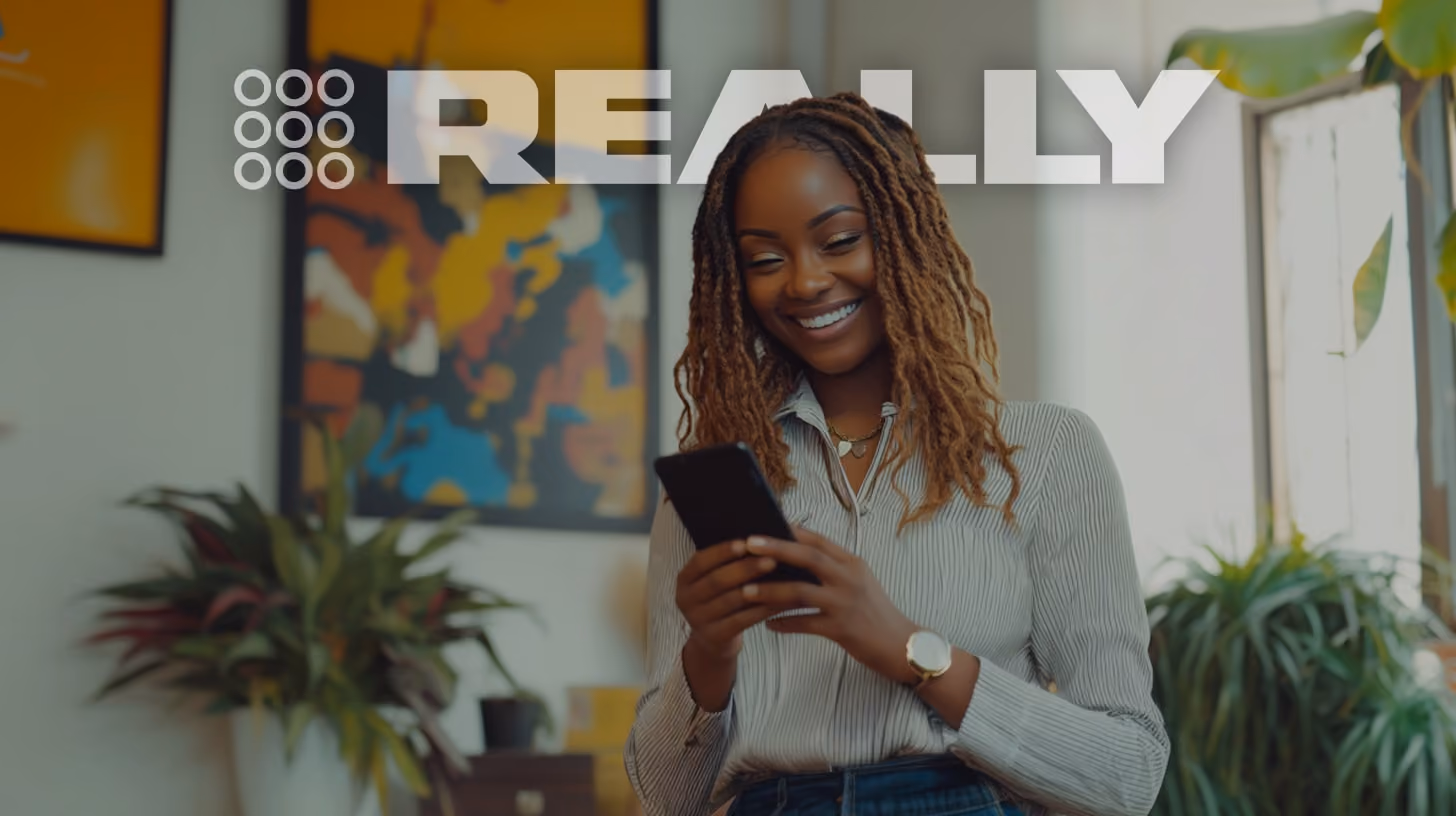 smiling woman watching on her phone, standing in her office, happy vibes