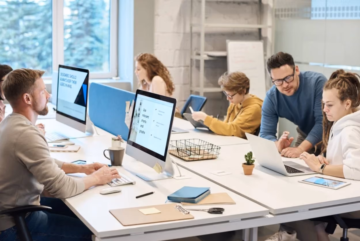 A diverse group of professionals collaborating at a desk in a modern office environment.