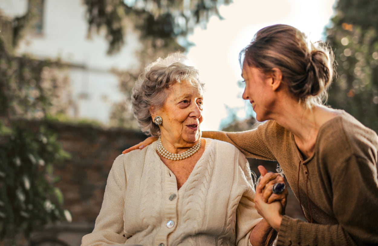 A woman engages in conversation with an older woman, both appearing attentive and interested in the discussion.