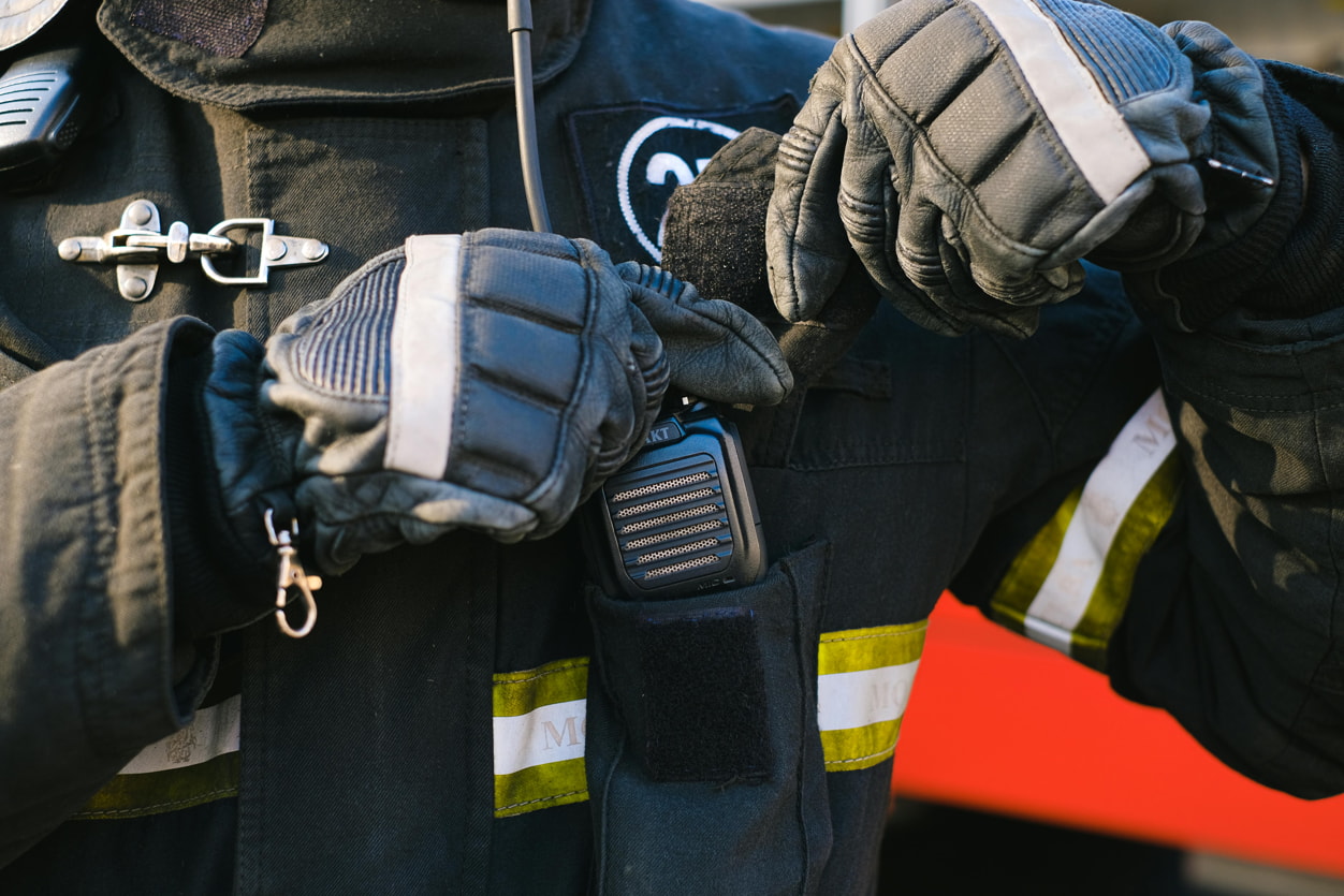 A firefighter in gloves and a helmet stands ready for action, showcasing their protective gear and commitment to safety.  