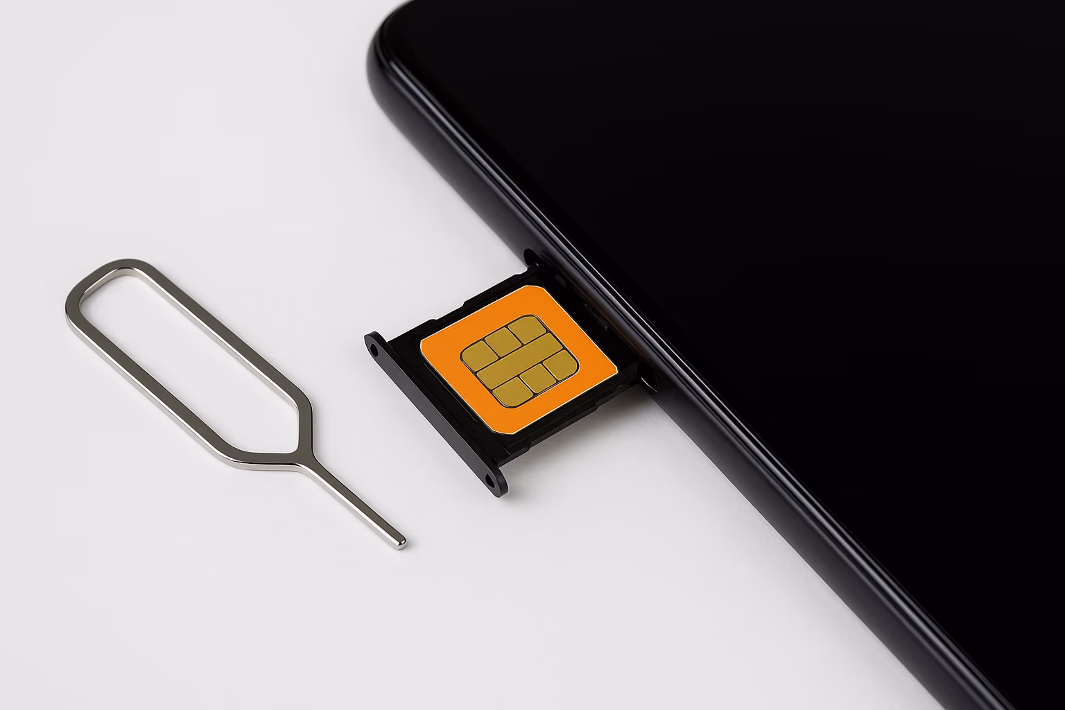 Sleek black smartphone on a clean white background, its SIM tray partially ejected to reveal an orange SIM card, with a silver SIM-ejector tool lying beside it.
