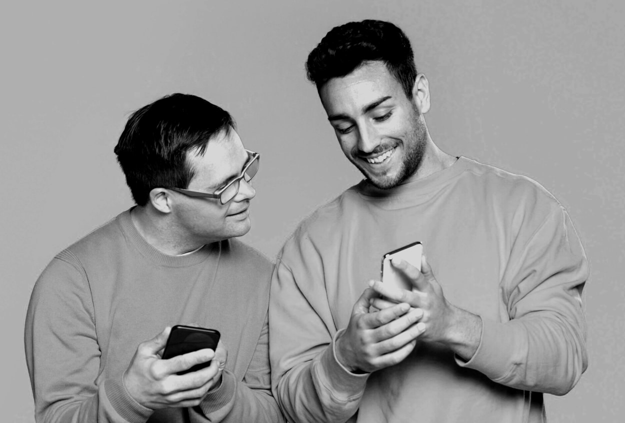 Smiley man showing something to his friend on the phone