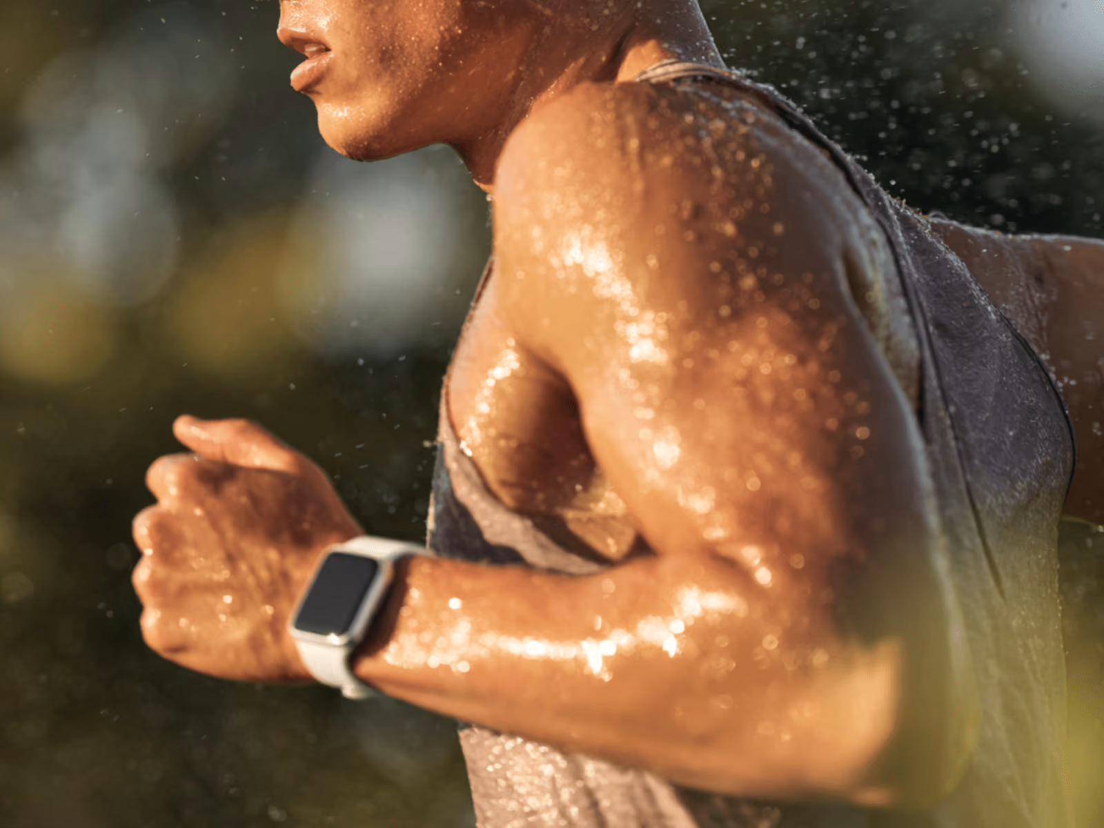 man running outdoors wearing an Apple Watch on his wrist, with sweat and sunlight highlighting his movement and fitness activity tracking.