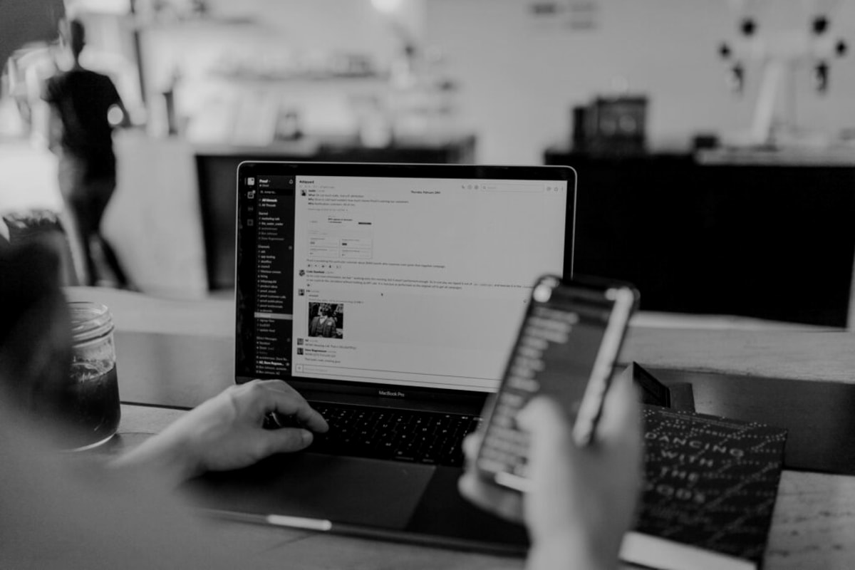 A man wearing headphones sits at a desk, focused on a computer screen in front of him. 