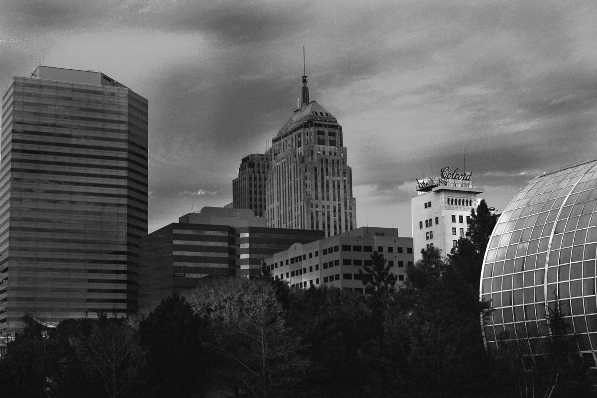 Urban skyline with towering buildings surrounded by lush trees. 