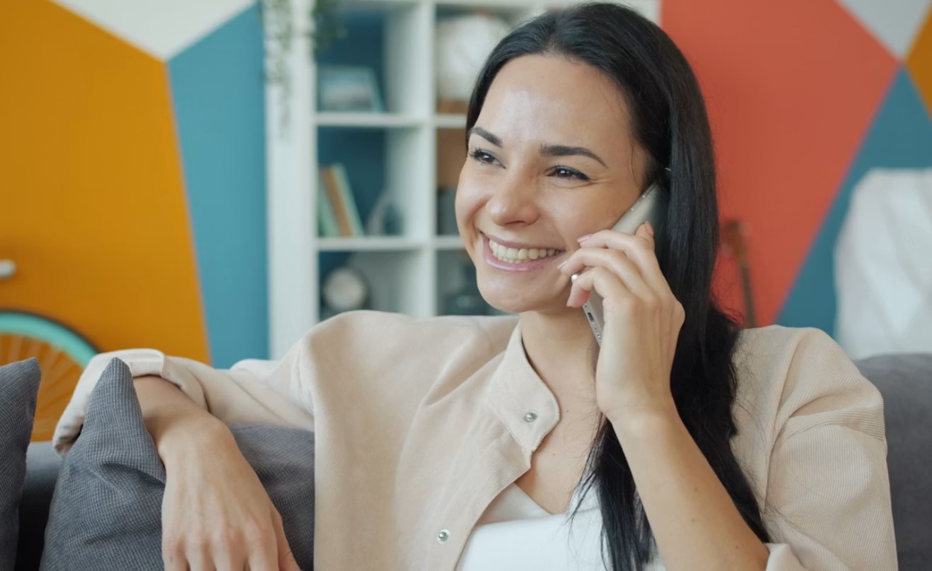 A woman with a cheerful expression speaks on her cell phone, indicating a pleasant interaction.