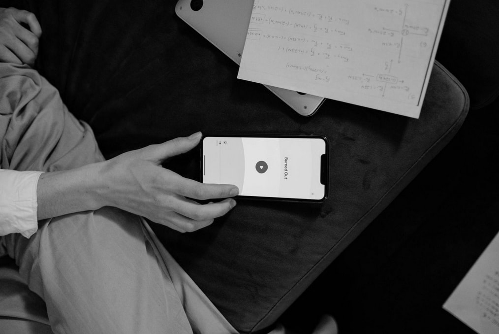 A person sitting on a couch, focused on their cell phone, with a relaxed posture and casual surroundings. 