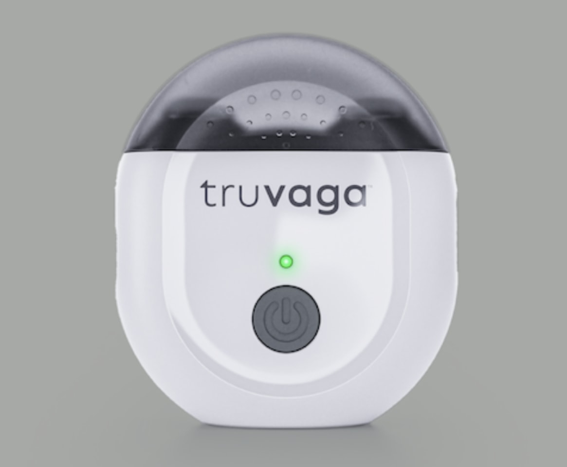 A white Truvaga device with a green light and power button on a gray background, indicating it's powered on and ready to use.
