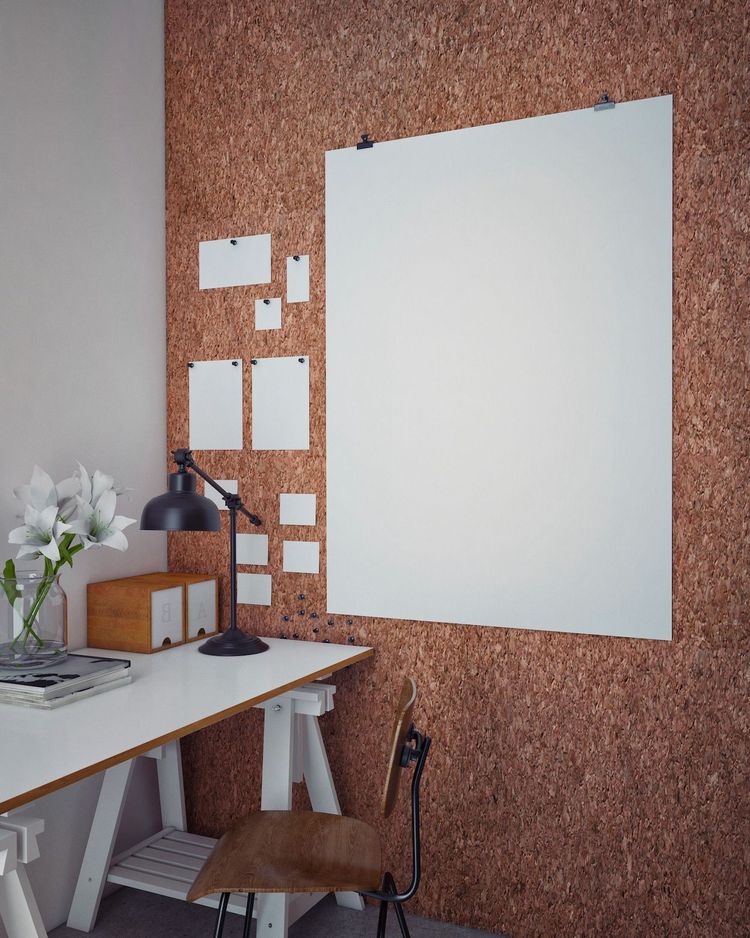Coin bureau moderne avec un mur en liège, un grand tableau blanc, une lampe de bureau noire, une chaise en bois et un vase avec des fleurs blanches.