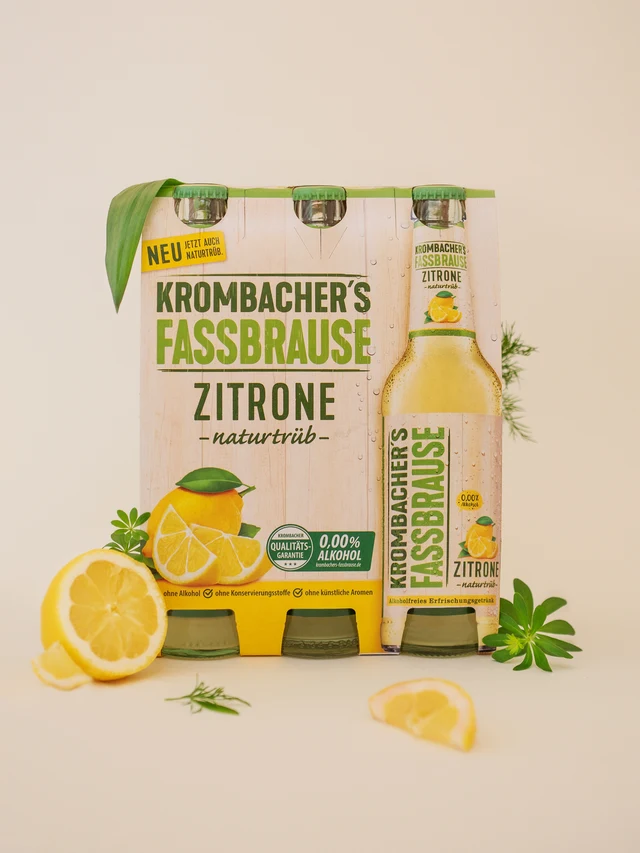 Pack of Krombacher's Fassbrause Zitrone natural lemon-flavored soft drink bottles with lemon slices and green leaves around.