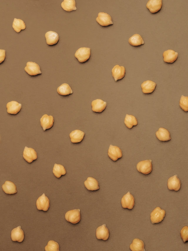 Scattered raw chickpeas on a brown surface.