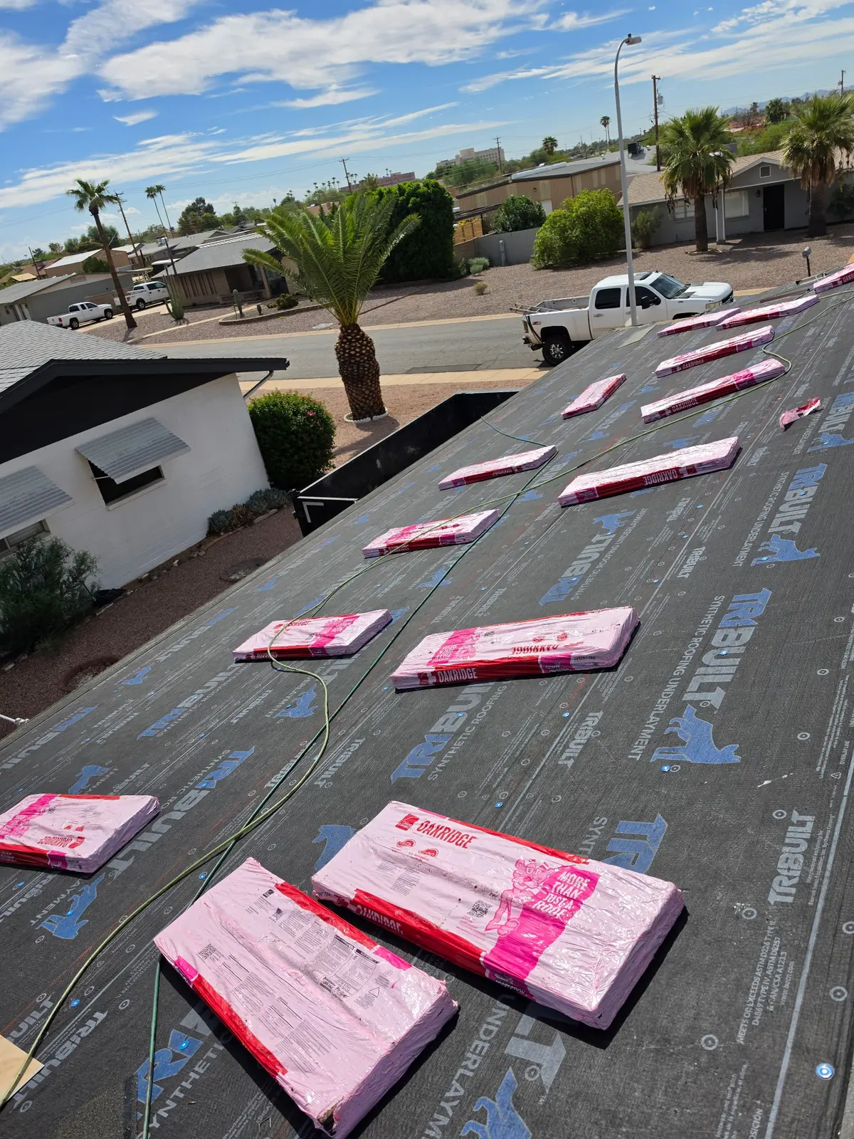 Architectural shingle bundles staged over synthetic underlayment in Mesa