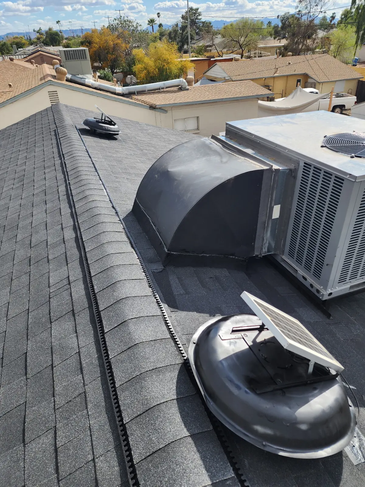 Finished shingles detailed around rooftop HVAC equipment