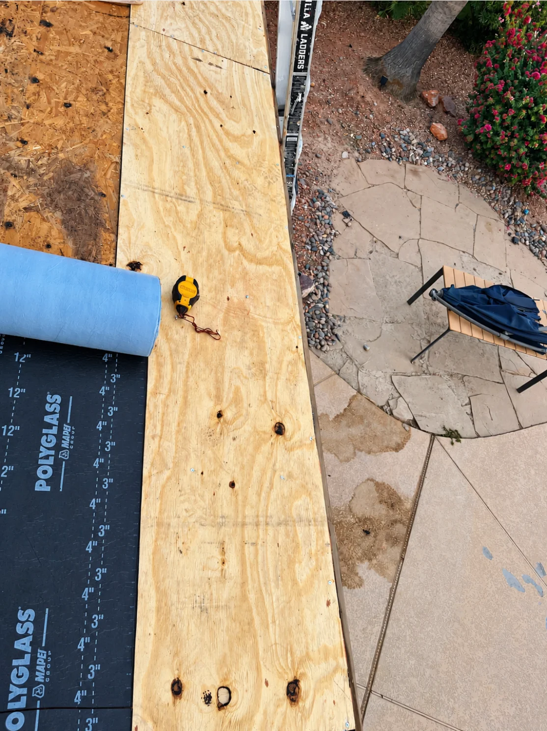 Exposed wood decking and roofing material at the edge of the Chandler roof