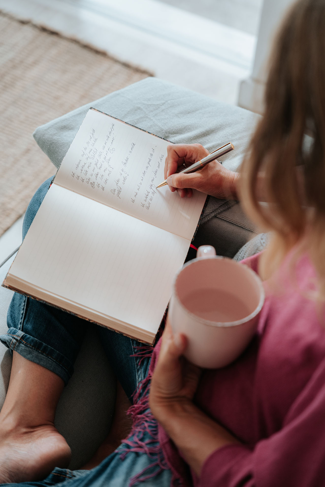 martina knall schreibt in tagebuch und haelt eine tasse kaffee