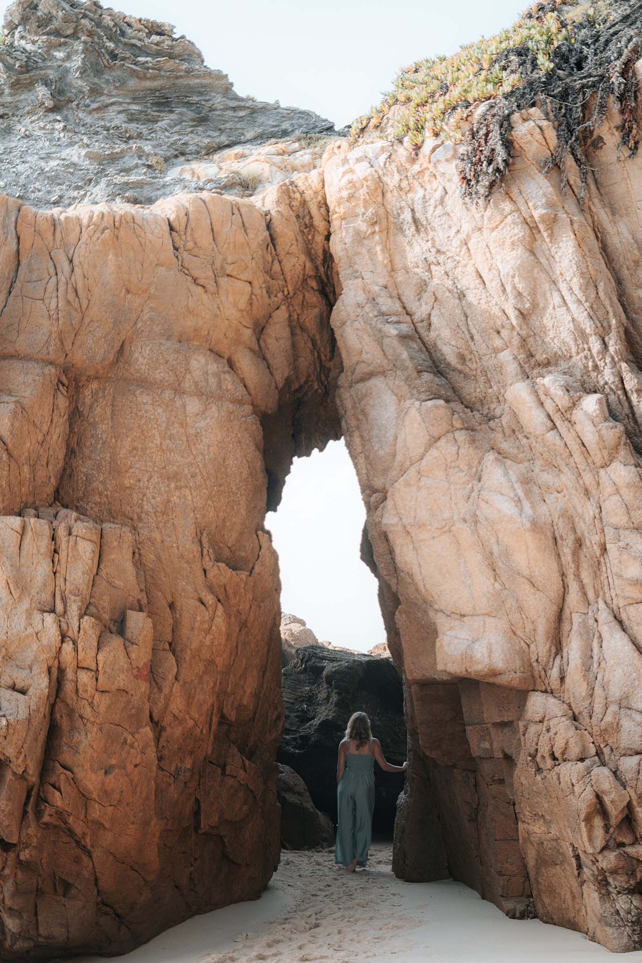 Frau geht durch eine schmale Felsöffnung in der Natur – Symbol für Übergang, innere Transformation und den Weg aus dem Burnout in ein selbstbestimmtes Leben.