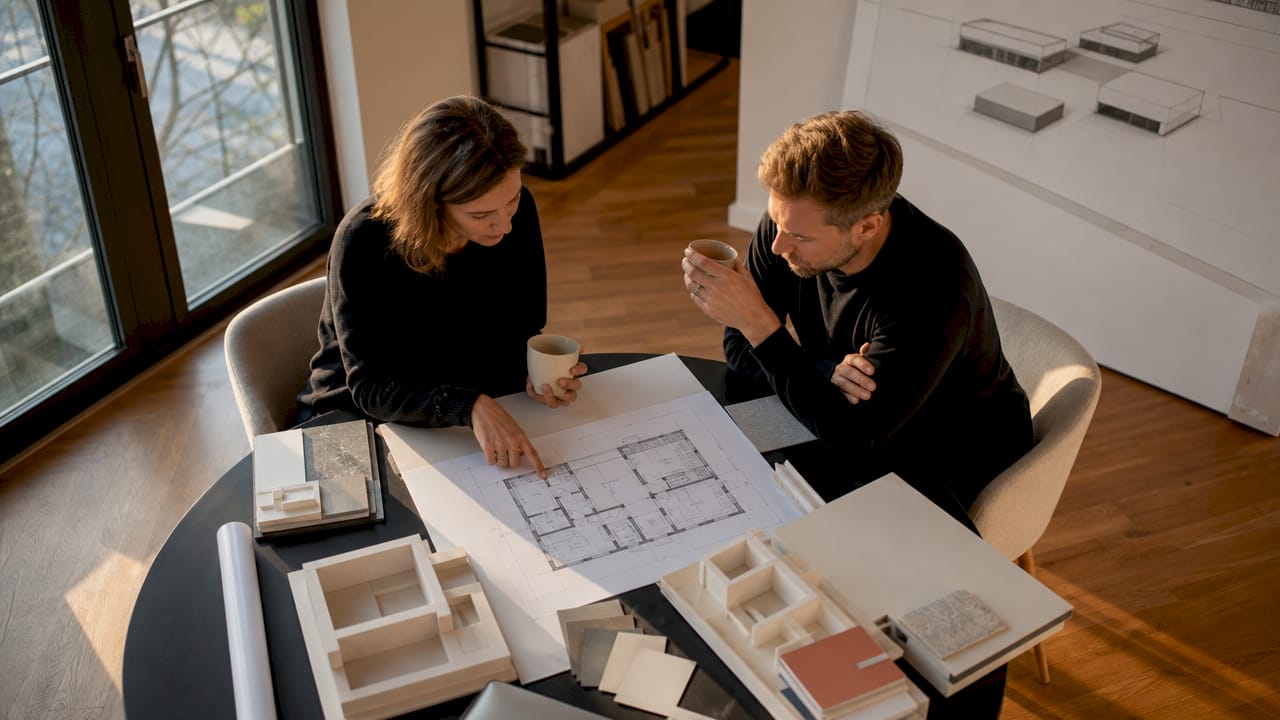Im offenen Loft-Atelier tauschen sich Architekten über die Planung eines Flachdachhauses aus.
