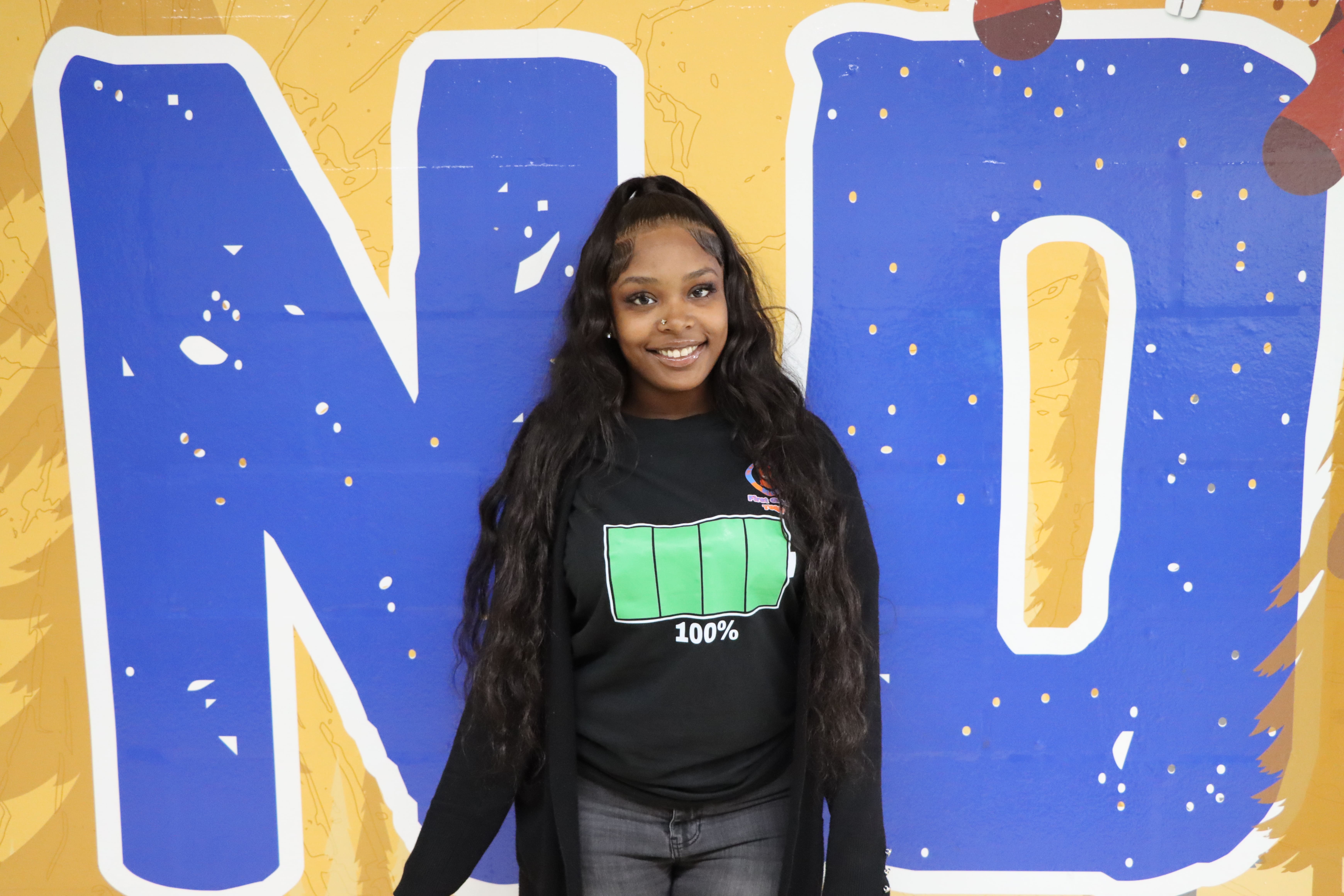 Student posing in front of large blue letters