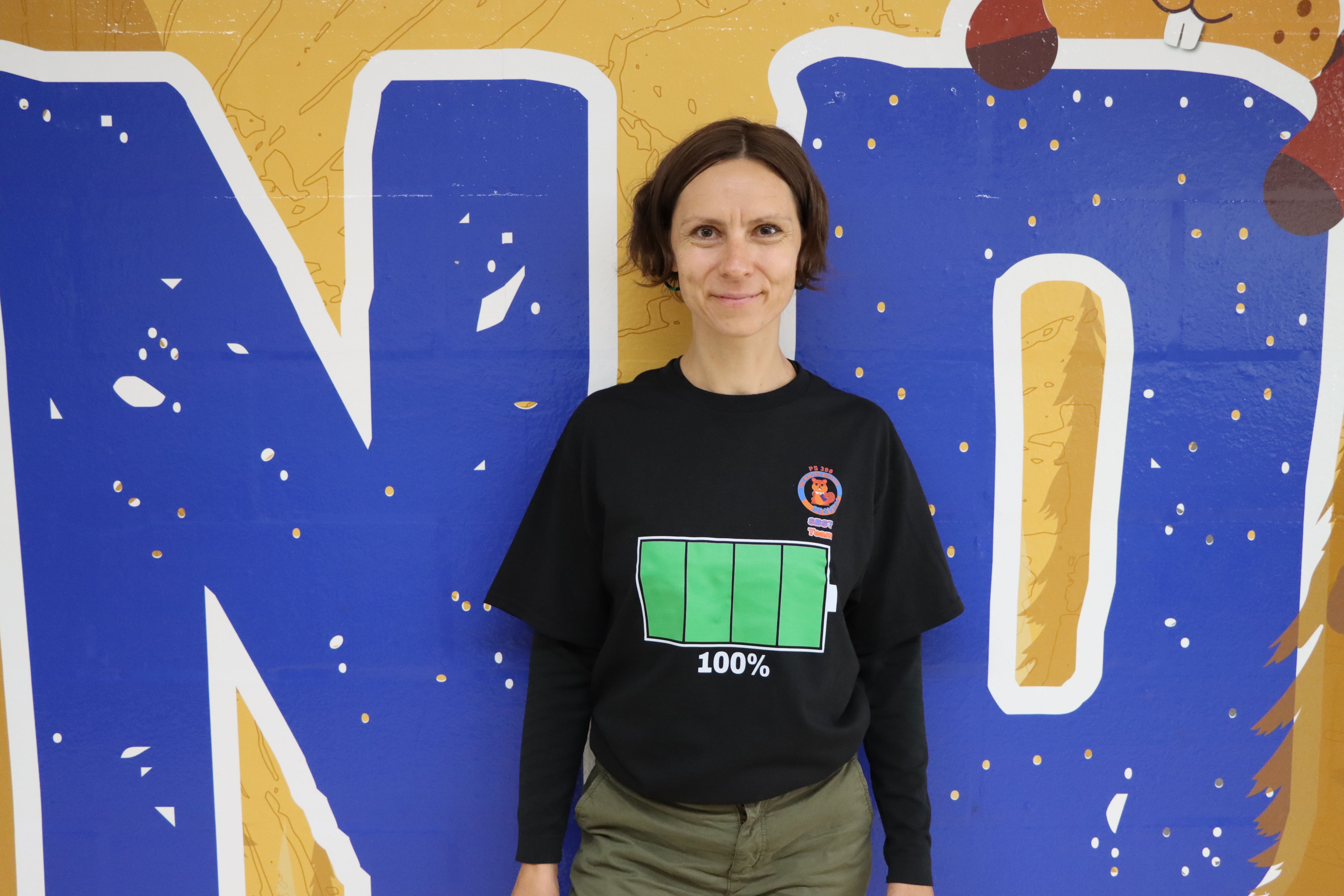 Staff member posing in front of colorful wall mural