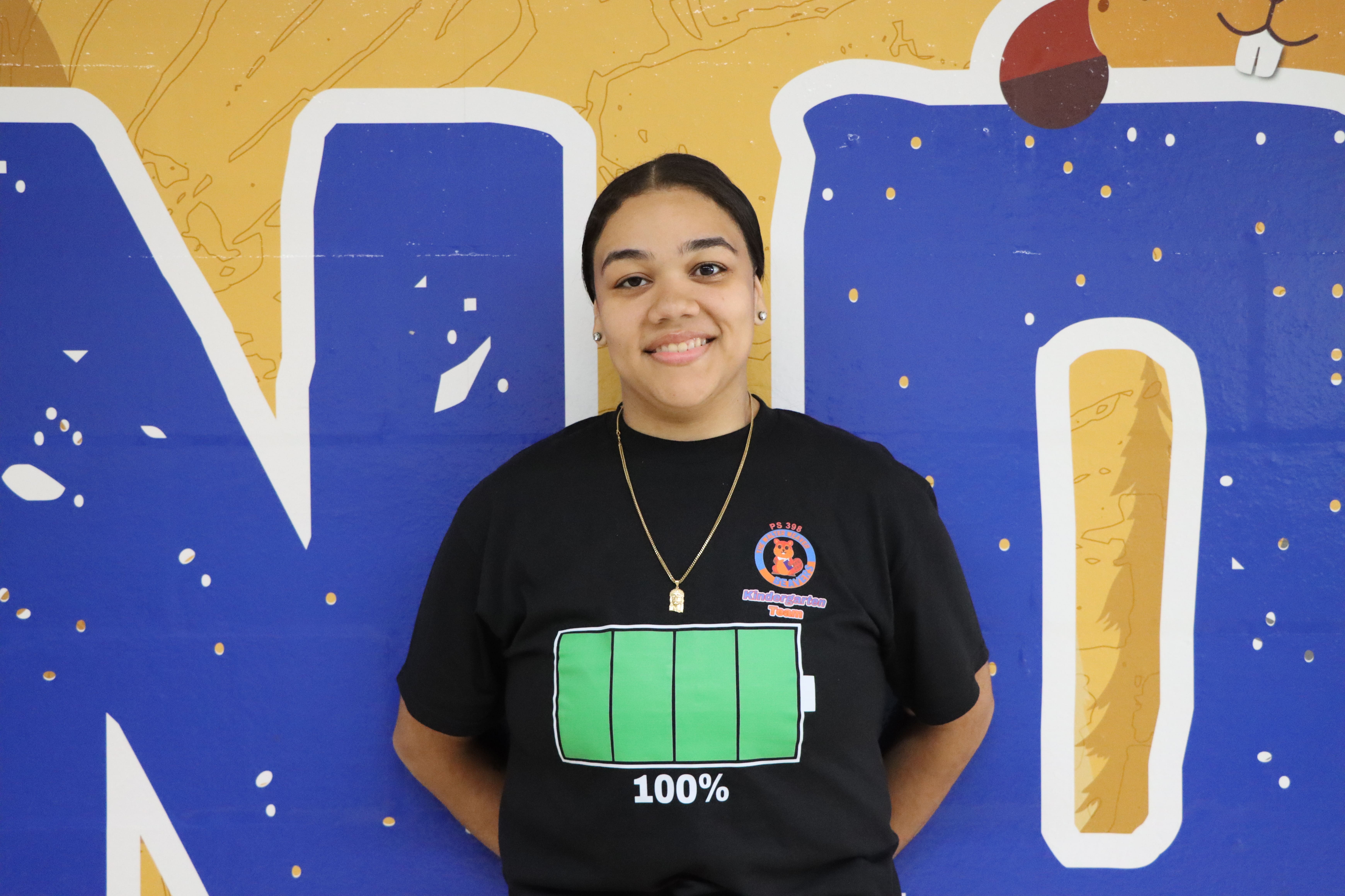 Staff member smiling in front of colorful mural