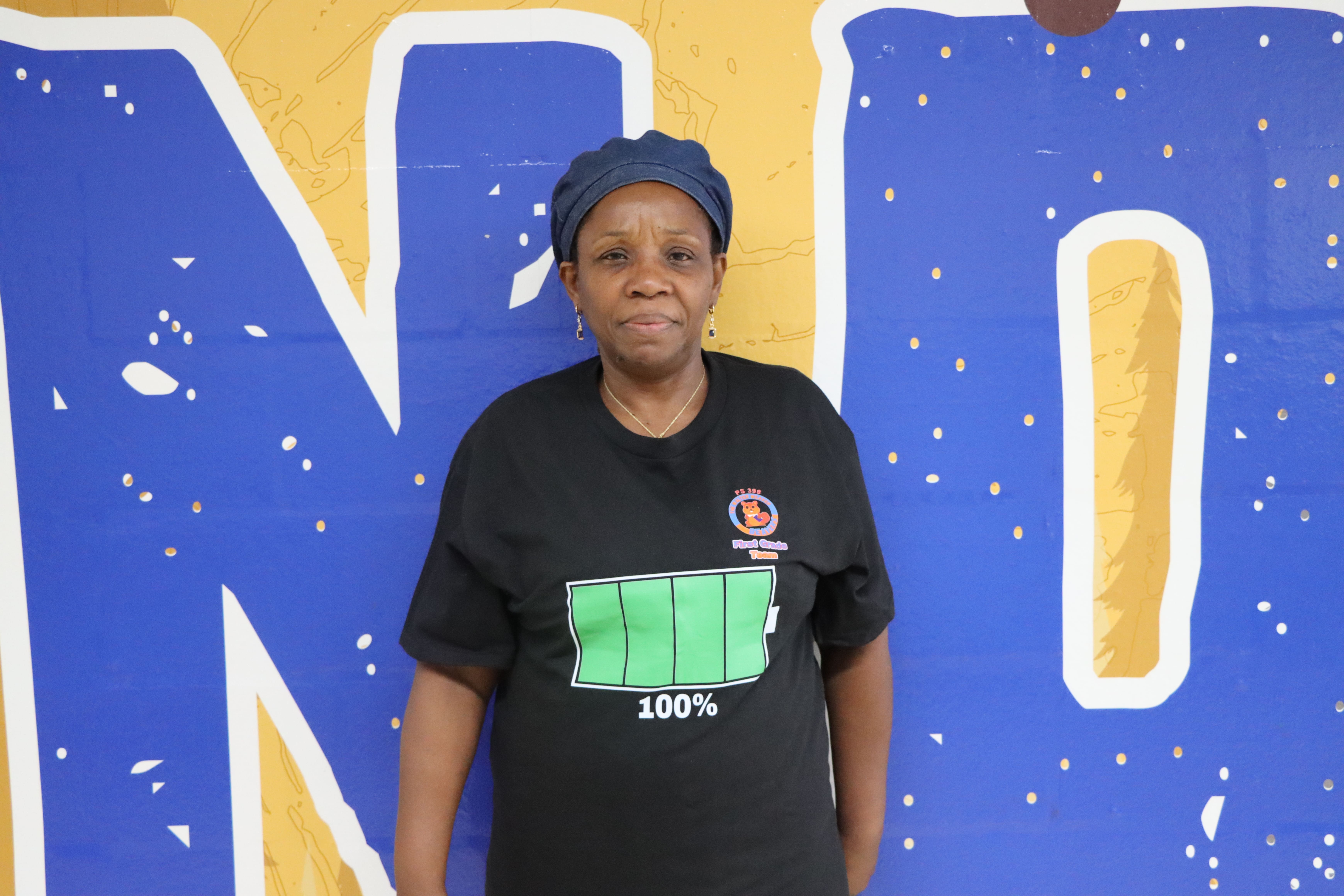 Staff member A. Fils-Aime in front of blue and yellow mural