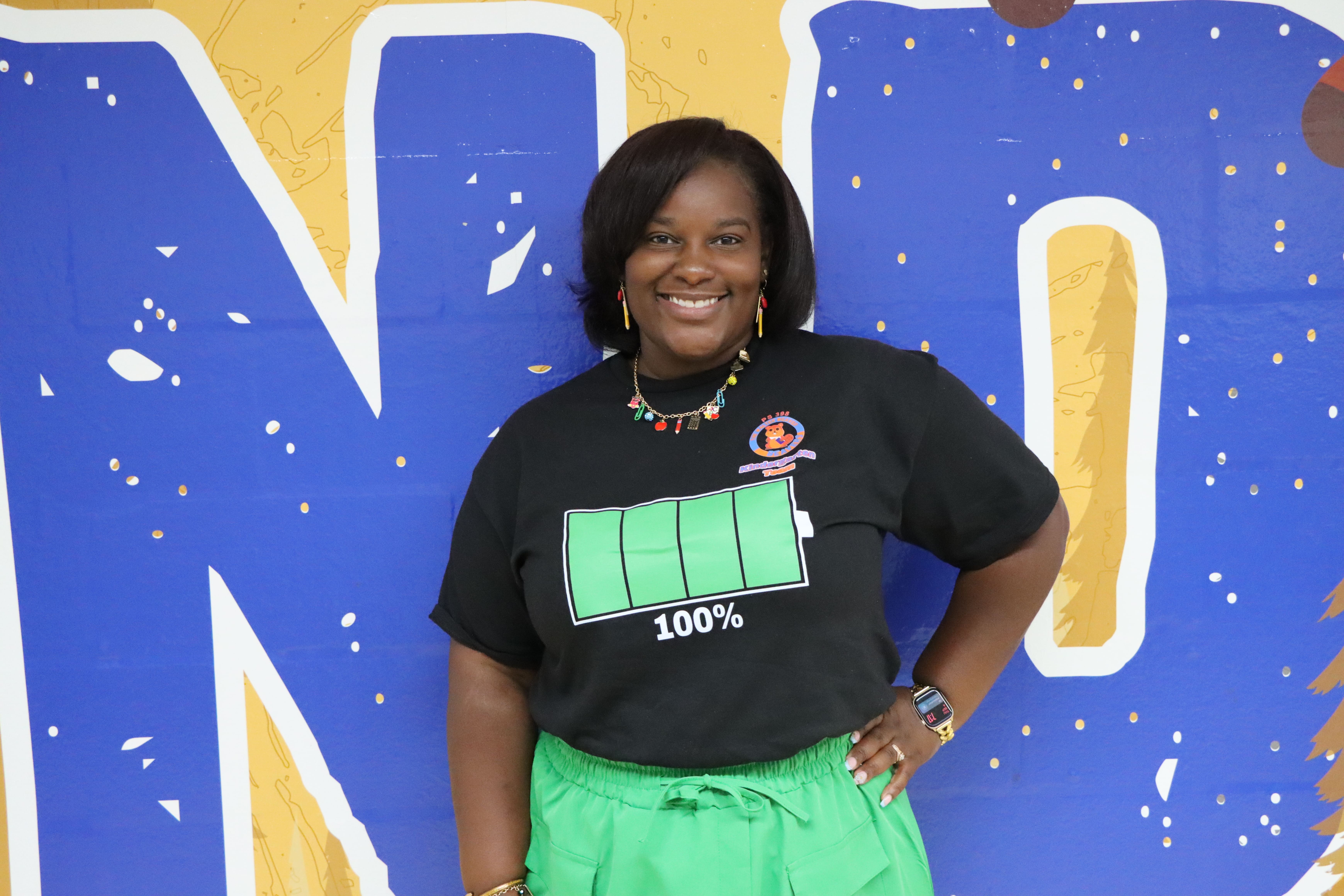 Student wearing battery icon shirt poses for portrait