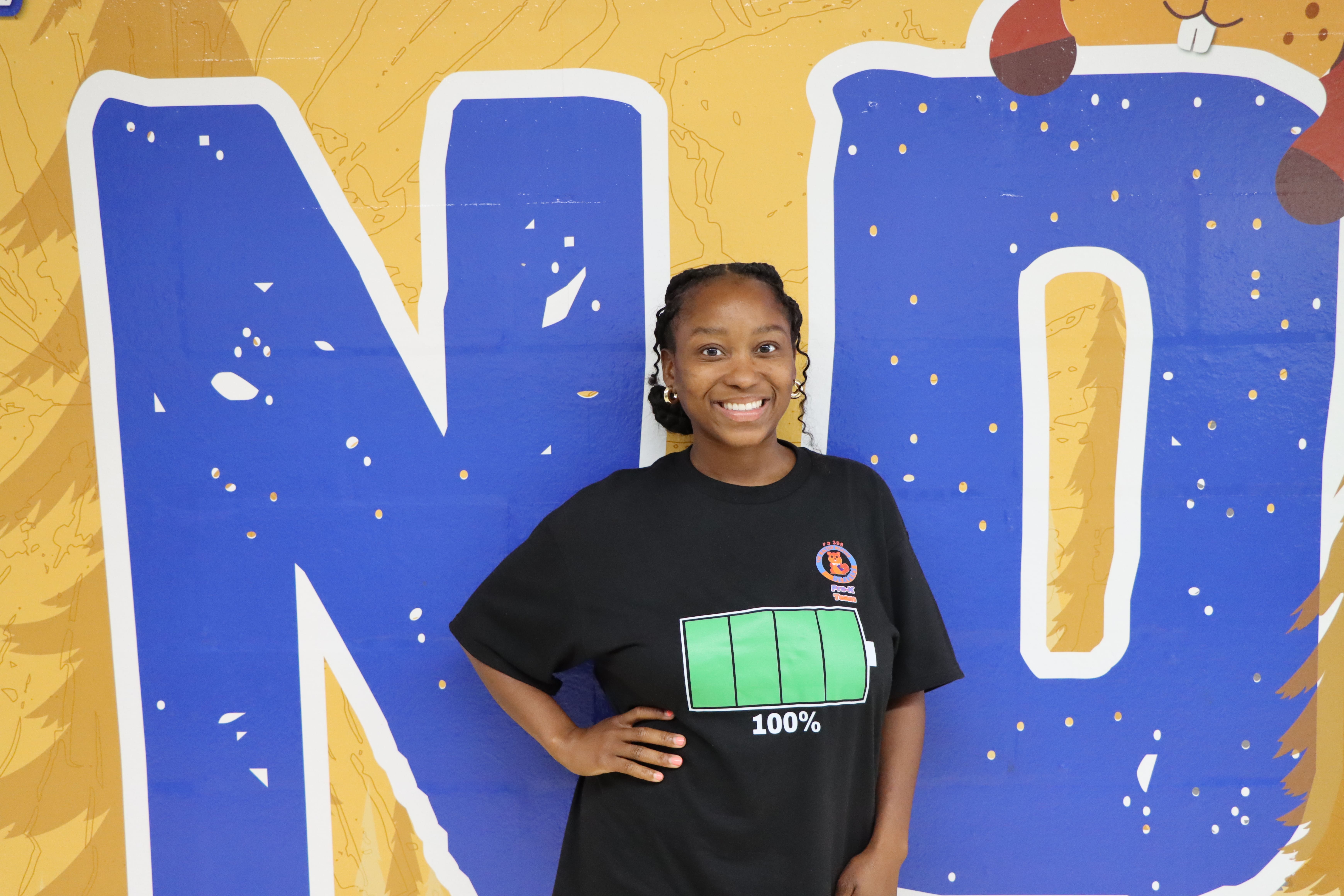 Student smiling in front of colorful mural