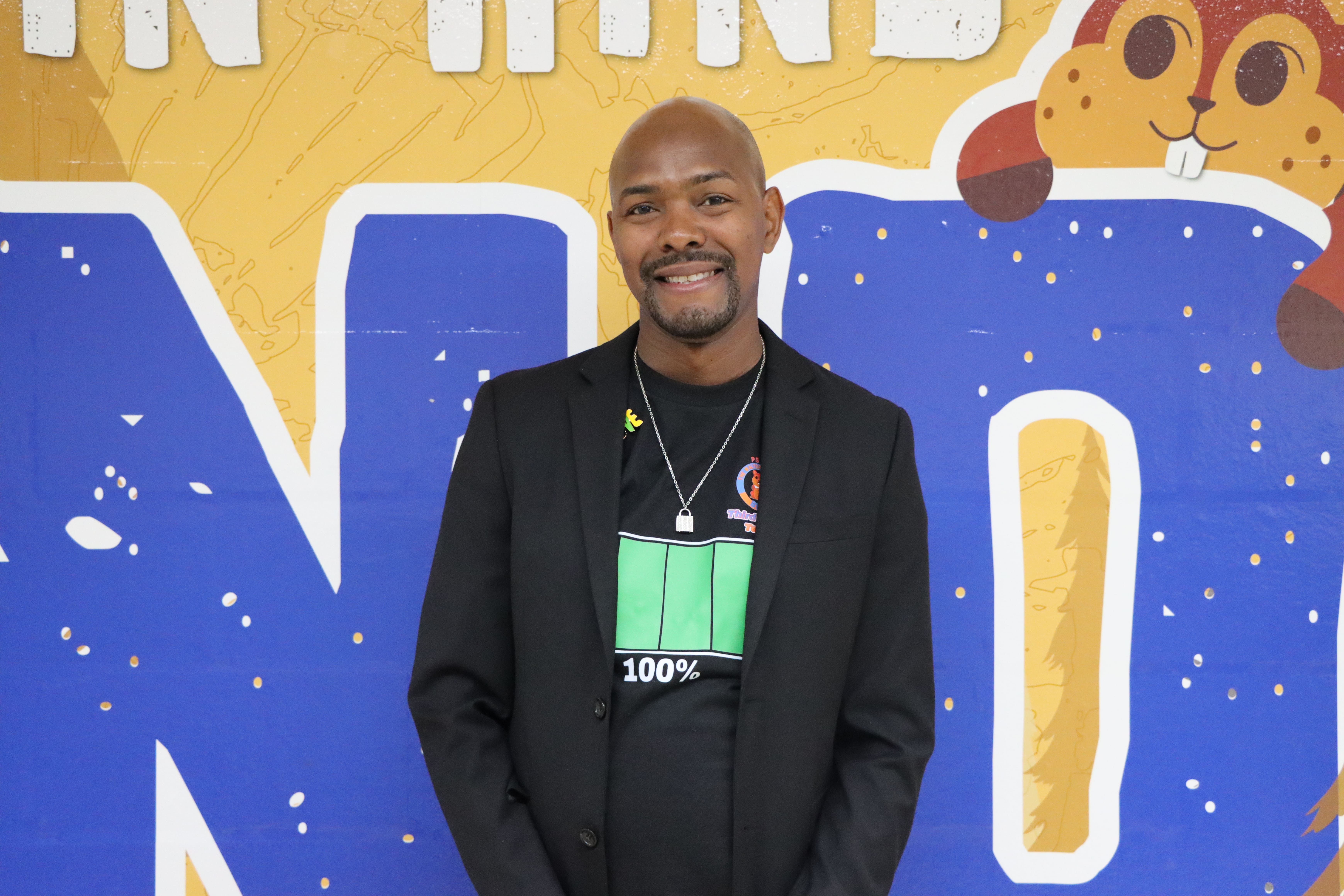 Staff member posing in front of colorful school mural