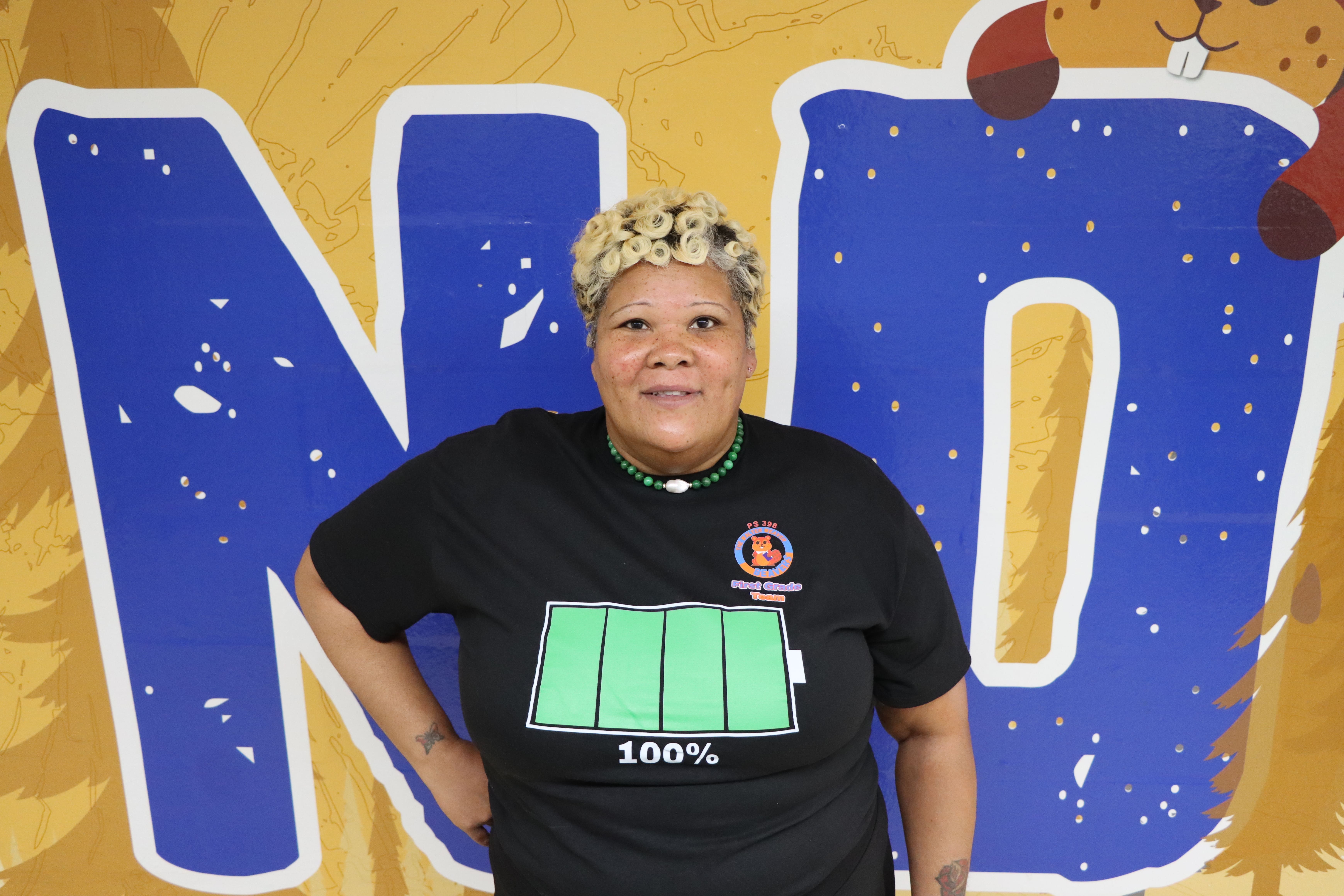 Staff member smiling in front of colorful mural