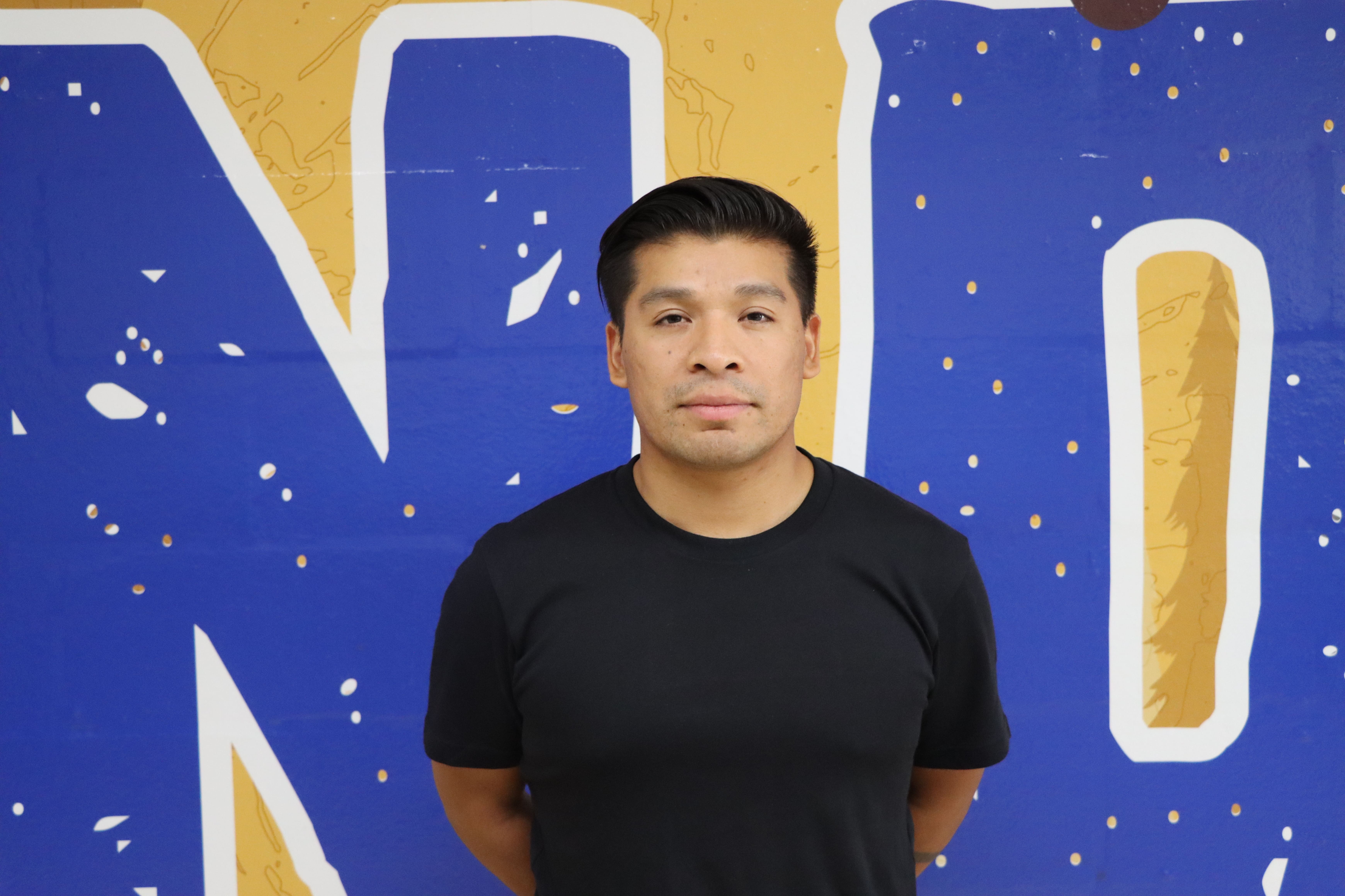 Staff member portrait photo against decorative blue and gold wall