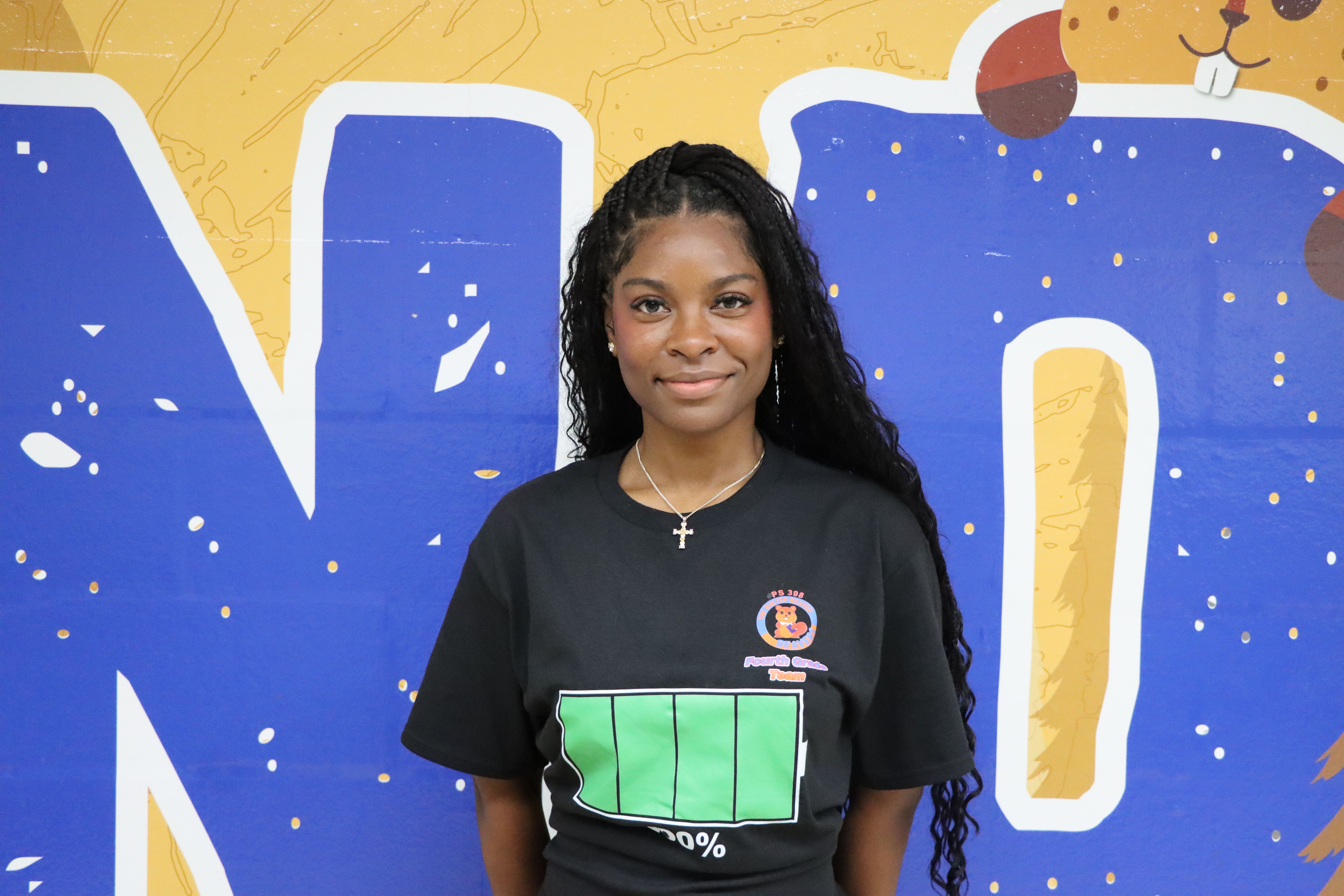 Staff member poses in front of colorful school mural