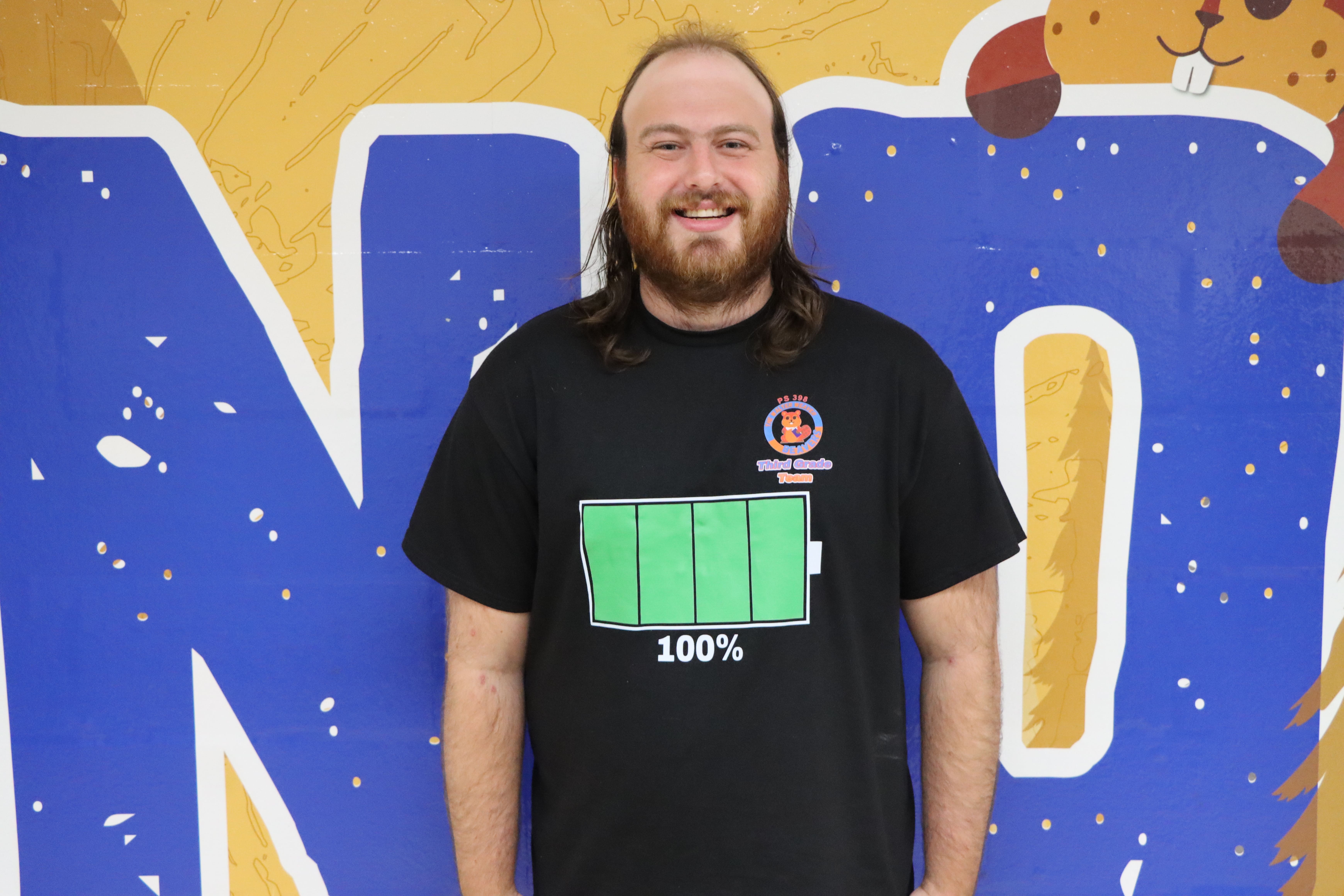 Staff member smiling in front of colorful mural