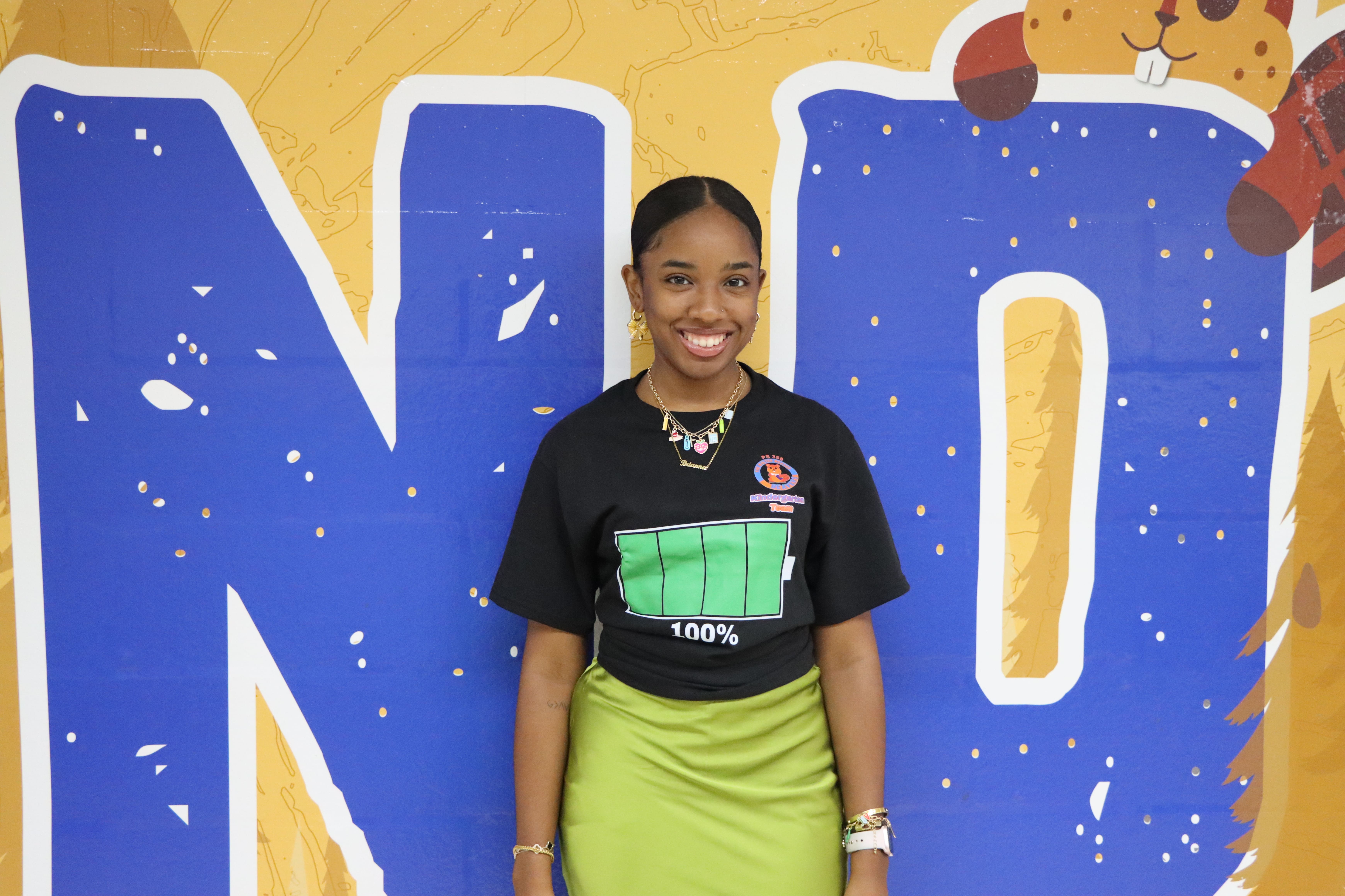 Student smiling in front of colorful blue wall mural