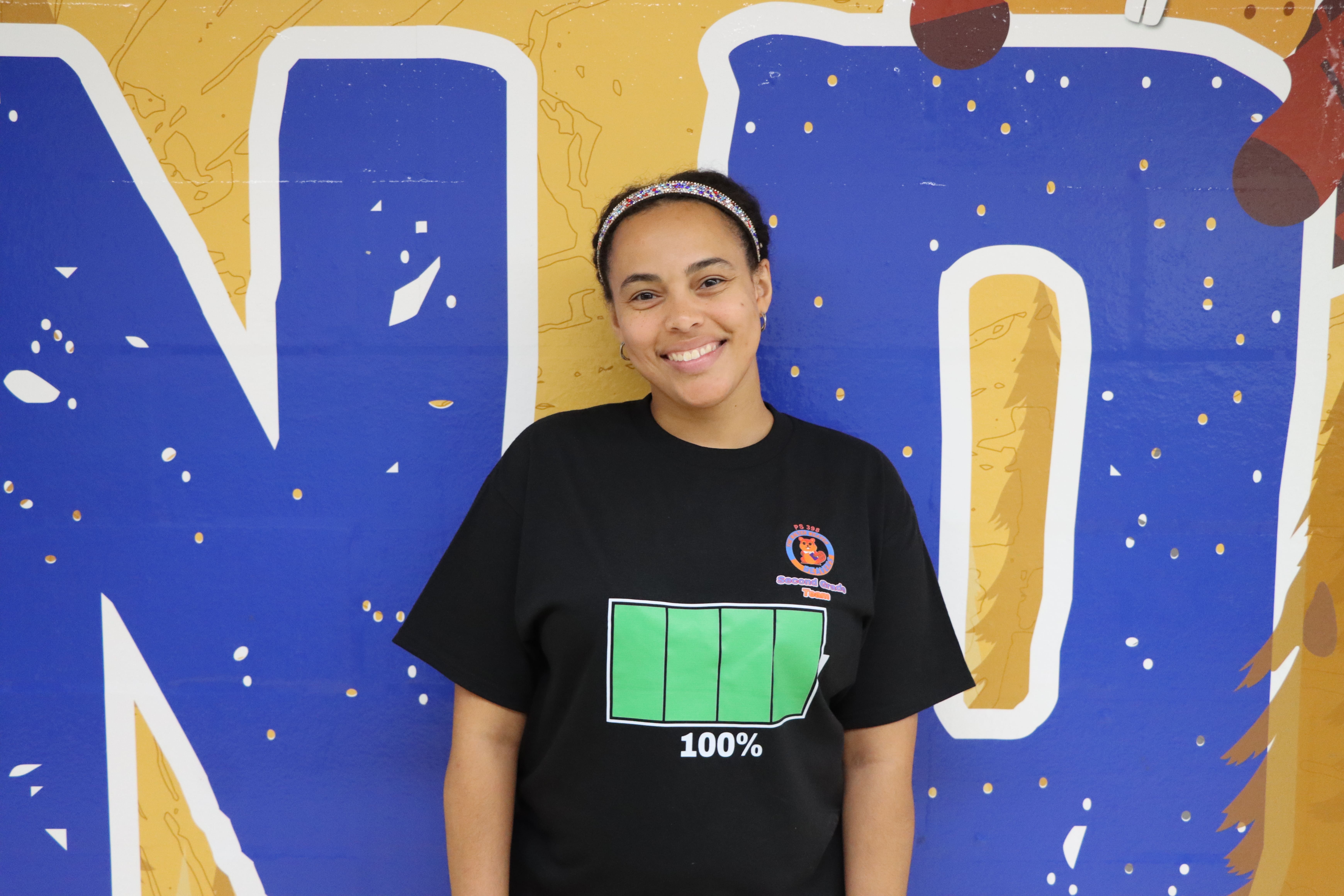 Student smiling in front of colorful mural wall